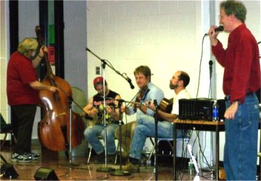 Taylor Runner calling the square dance with several musicians playing instruments