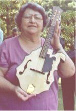 Bonnie Collins showing off a mandolin shaped like West Virginia